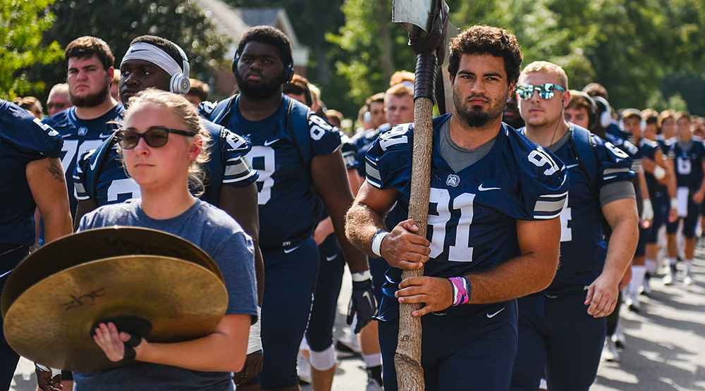 Berry's Bryson Lamboy, carrying a large ax, follows a crash cymbals player and leads a line of Berry Vikings in uniform before the team's season opener. (Berry athletics photo)