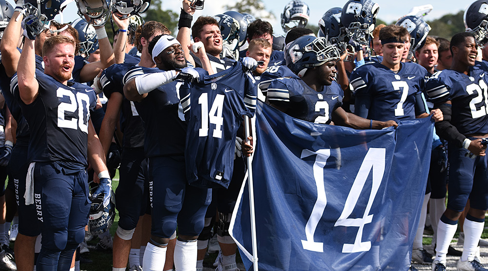 Justus Edwards' teammates hold up his uniform and a banner with Edwards' No. 14 on it. (Berry athletics photo)