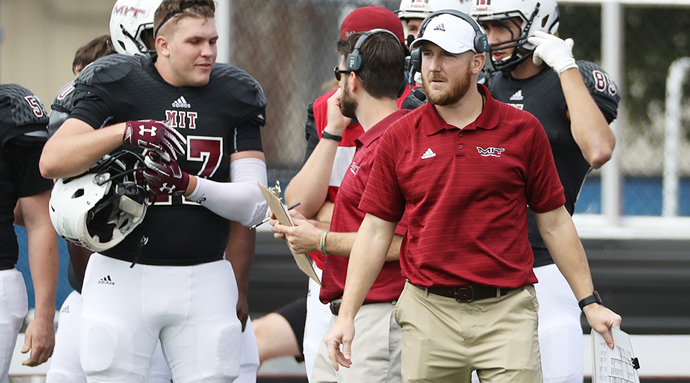 Brian Bubna, with a headset on, walking the sidelines for MIT. (MIT athletics photo)
